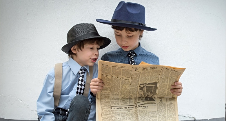 two boys reading a newspaper