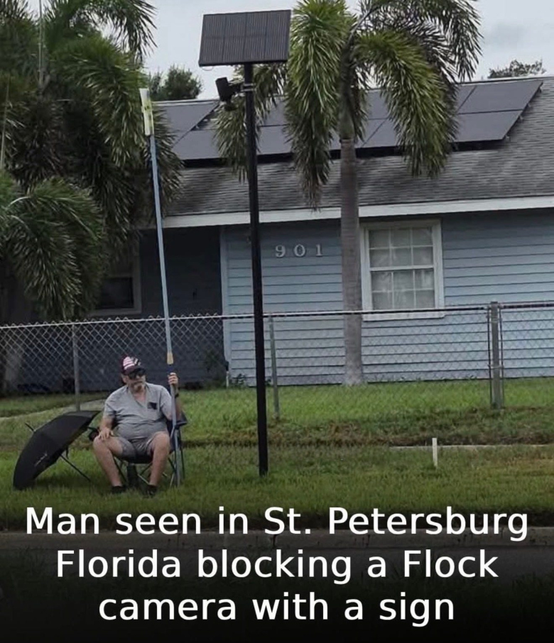 image of man using a sign to block a Flock camera
